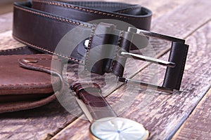 Set of men`s accessories for the business with leather belt, wallet, watch and smoking pipe on a wooden background. The