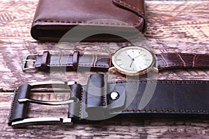 Set of men`s accessories for the business with leather belt, wallet, watch and smoking pipe on a wooden background. The