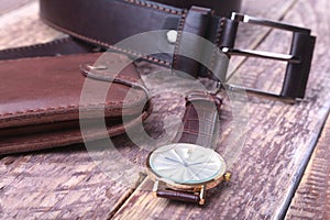 Set of men`s accessories for the business with leather belt, wallet, watch and smoking pipe on a wooden background. The