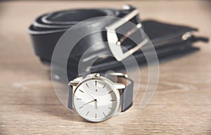 Set of men`s accessories for the business with leather belt, wallet, watch and smoking pipe on a wooden background