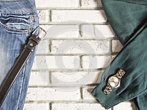 A set of men`s clothing and accessories on a gray brick wall background. Casual dark blue and green clothing