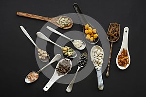 Set of messy spoons of different materials and shapes filled with nuts