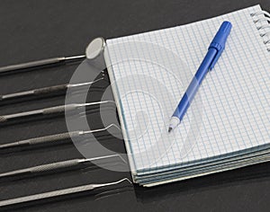 Set of metal Dentist`s medical equipment tools with notebook and marker