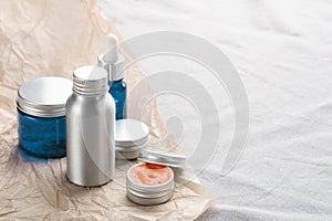 Set of metal and glass containers of natural cosmetic products on fabric