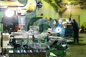 A set of metalworking tools in front of manual vertical milling and boring oldschool machine indoors