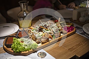 set of mixed meat with salad and sauce on a board with lemonade for a company on a table, horizontal