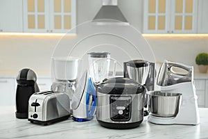 Set of modern home appliances on white table in kitchen