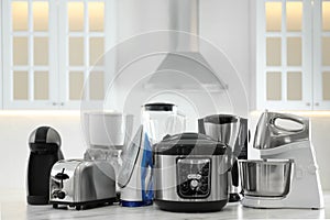 Set of modern home appliances on white table in kitchen