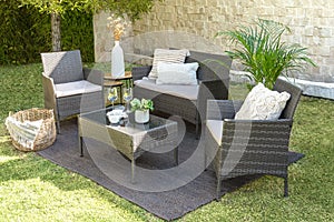 Set of modern outdoor rattan furniture in a green garden.