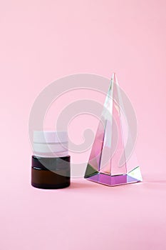 Set moisturizer cream jars and glass pyramid prism on pink background with copy space, vertical. Beauty skin care