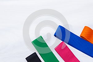 A set of multi-colored elastic rubber bands for fitness on white wooden background. Fitness trend, sport concept