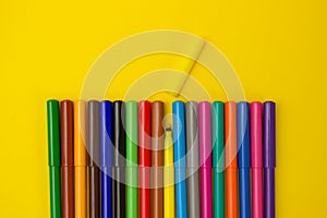 Set of multi-colored felt-tip pens pencils on a yellow background