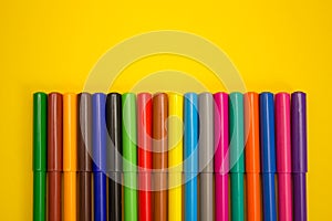 Set of multi-colored felt-tip pens pencils on a yellow background