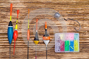 Set of multi-colored floats for fishing, sinker and hook, on a dark wooden background