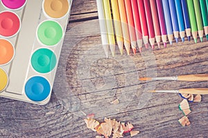 Creativity: Multi-colored pencils, water colors and brushes on rusty wooden table