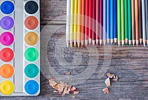 Creativity: Multi-colored pencils, water colors and brushes on rusty wooden table