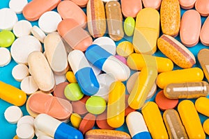 Set of multi-colored tablets and capsules on a blue background