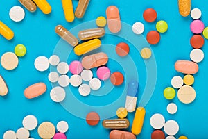 Set of multi-colored tablets and capsules on a blue background