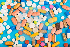 Set of multi-colored tablets and capsules on a blue background