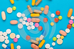 Set of multi-colored tablets and capsules on a blue background