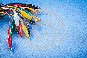 Set of multicolored electric crocodile plugs on blue background