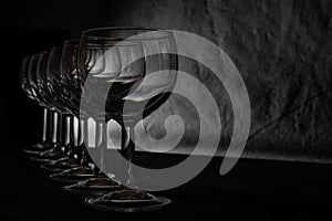 Set of multiple glasses shot in low-key lighting over the black background. Smooth lines and shapes. Concept.