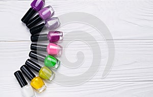 Set of nail polish bottles in different color on white wooden background