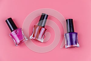Set of nail polish bottles on pastel pink background. Top view