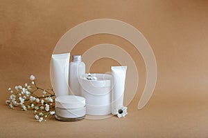 Set natural beauty cosmetic skincare products with flowers sea shells on beige background with copy space. White kit