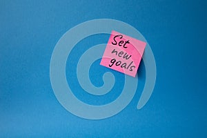 Set New Goals symbol. Concept words Set New Goals on pink steaky note. Beautiful blue background. Business and Set New Goals