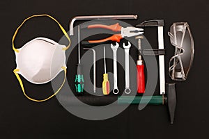 A set of new hand tools, mask, glasses and gloves on a black background