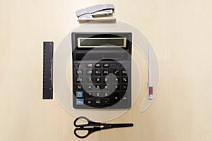 A set of office tools consisting of a calculator, pen, stapler,