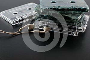 Set of old audio cassettes with earphones on a black floor.