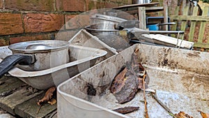 A set of old baking trays and pots in a childs outdoor mud kitchen