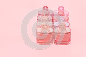 Set of open nail polish bottles without brushes. Group of nail polish isolated on pink background. Copy space