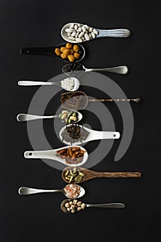 set of ordered spoons of different materials and shapes filled with nuts,