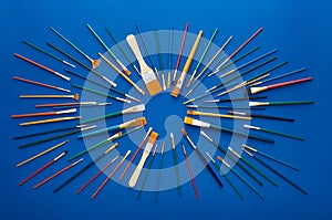 Set of paint brushes in circular burst pattern. Flat lay shot, blue background