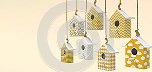 A set of painted birdhouses are suspended on a rope. Birdhouses with yellow and white patterns isolated on a light yellow backgrou