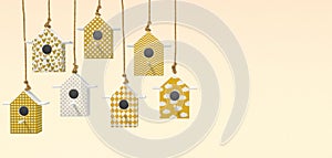 A set of painted birdhouses are suspended on a rope. Birdhouses with yellow and white patterns isolated on a light yellow backgrou