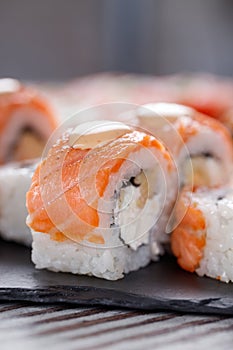 Set of Philadelphia sushi on black concrete plate on table.