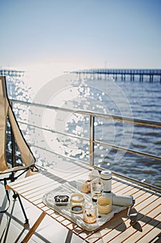 Set of picnic camping with folding chair and table, Manual grinder and coffee press, beautiful bright sky and ocean.