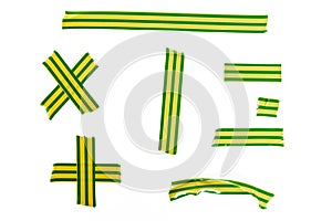 A set of pieces of torn green and yellow striped duct tape isolated on white