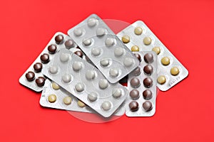 Set of pills blisters isolated on solid red background. Medical concept.  Potent drugs. White, brown and yellow pills. photo