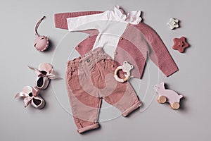 Set of pink clothes and accessories fot newborn girl. Toys, bodysuit, jeans, knitted cardigan on grey backgroundd. Mock