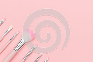 Set of pink makeup brushes on pastel pink background