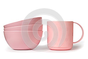 A set of pink plastic dishes on a white background.
