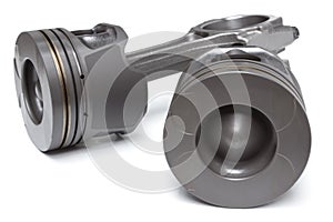 A set of pistons and rods for automobile engine on a white background