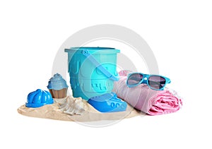 Set of plastic beach toys, blanket, sunglasses and pile of sand on white