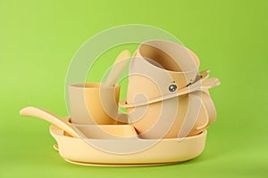 Set of plastic dishware on light green background. Serving baby food