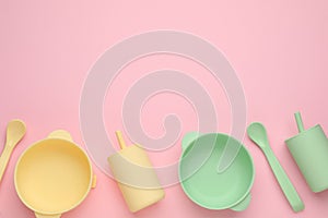 Set of plastic dishware on pink background, flat lay with space for text. Serving baby food
